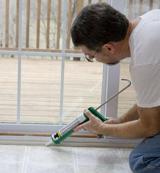 Man Placing Caulking Around Doors